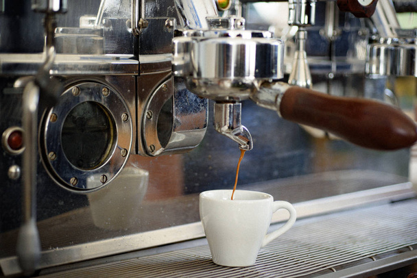 für Kaffeeliebhaber. Espresso, der in Kaffeehäusern oder Cafés gebraut wird. Herstellung von Espresso mit Portafilter. Kaffeetasse vorhanden. kleine Tasse, um heißen Kaffee zu servieren. Kaffee brauen mit Espressomaschine - Foto, Bild