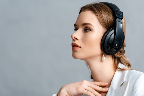 portrait of beautiful woman listening music in headphones and looking away with copy space - Foto, Imagen