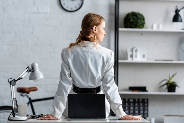 Rückansicht einer Geschäftsfrau in formeller Kleidung, die am Computer-Schreibtisch am Arbeitsplatz sitzt - Foto, Bild