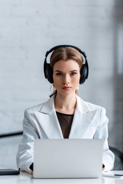 focused businesswoman in headphones sitting at computer desk at workplace                           - Zdjęcie, obraz