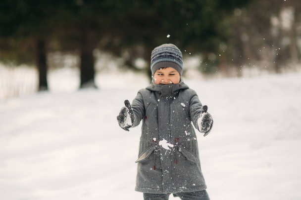 Pieni poika kävelee puistossa talvella sää, pelata lumipalloja ja iloitsi. Odotetaan joulun tunnelmaa
 - Valokuva, kuva