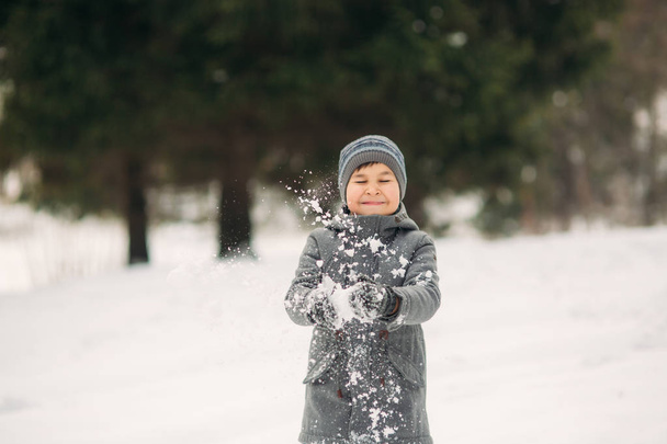 A little boy walks in the park in the winter weather, play snowballs and rejoiced. Waiting for Christmas mood - Photo, image