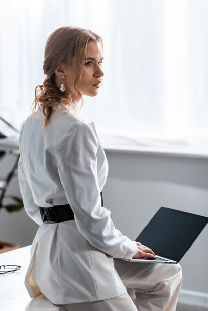 職場でノート パソコンを使用して白のフォーマルな服装の美しい女性実業家 - 写真・画像