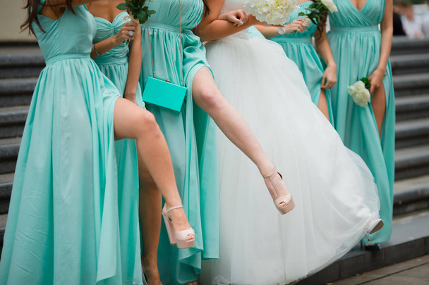 Bridesmaids legs. Dressed in blue dresses. On the background of stairs - Photo, Image