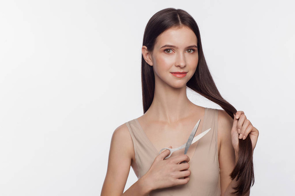 Portrait of beautiful young woman cuts off her hair by scissors - Foto, afbeelding