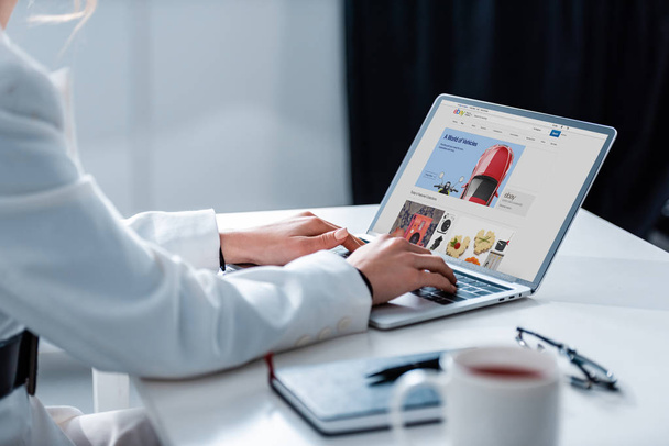 обрізаний погляд жінки, використовуючи ноутбук з ebay сайт на екрані в офісному столі - Фото, зображення