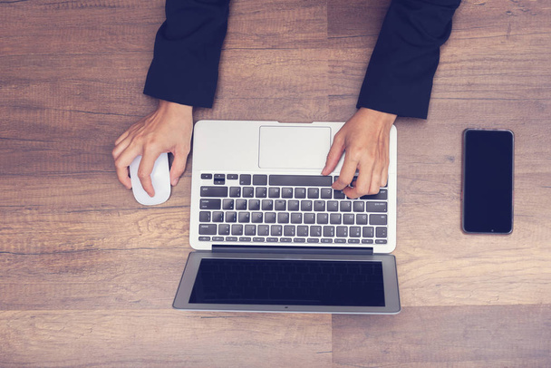 бізнесмен працює ноутбуком на дерев'яному фоні, азіатський бізнесмен працює або шукає в комп'ютері ноутбука
  - Фото, зображення