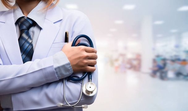 mulher médico cruzou o braço e segurando estetoscópio no departamento de pacientes desfocado, conceito médico
  - Foto, Imagem