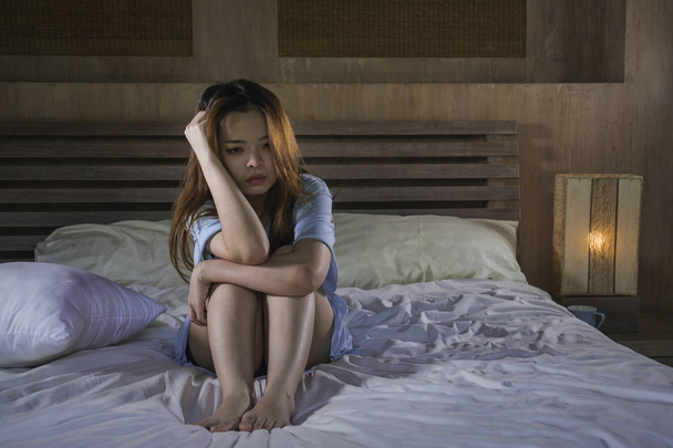 young beautiful and depressed Asian Korean woman crying on bed at night having depression problem and anxiety crisis feeling sad in girl suffering broken heart or cyber bullying concept - Foto, Imagem