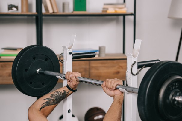 cropped view of man with tattoo workout with barbell in home gym  - Foto, Imagem