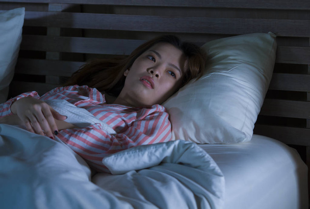 молодий красивою сумних та депресія азіатських китайської дівчини лежачи на ліжку пізньої ночі awake дивлячись продуманий страждає безсонням, спальний розлад відчуття втоми і турбуються за жінка депресії концепції - Фото, зображення