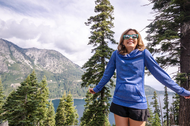 Νεαρή ενήλικη γυναίκα ψάχνει ανανεωμένοι, επαναφορτιστεί και ενθουσιασμένος για να περάσουν την ημέρα στα βουνά στο Emerald κόλπο στη νότια λίμνη Tahoe Καλιφόρνια - Φωτογραφία, εικόνα