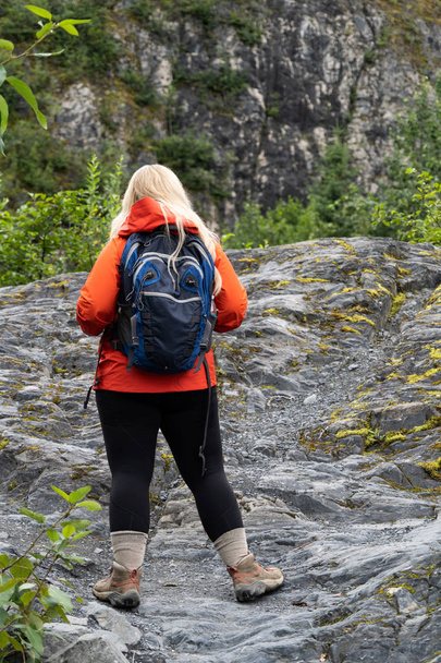 Blond kobieta turysta podchodzi szlak śliskie skały pokryte w Licheniu w Parku Narodowego Kenai Fjords noszenia plecaka. Na Alasce Seward - Zdjęcie, obraz