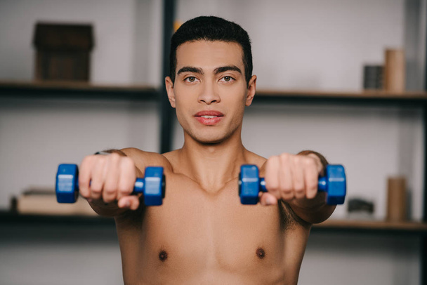 selective focus of bi-racial man exercising with blue dumbbells - Foto, immagini