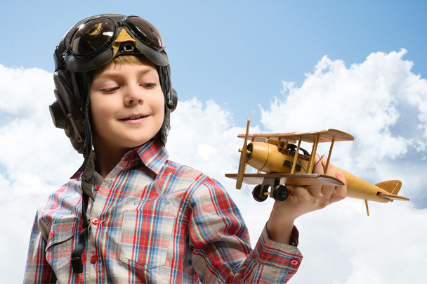 Boy in helmet pilot playing with a toy airplane - 写真・画像