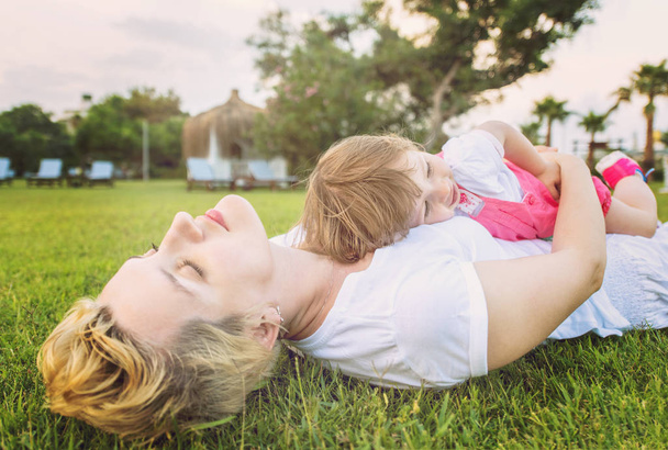 Young Mother and cute little daughter enjoying free time playing outside at backyard on the grass, happy family in nature concept - Fotoğraf, Görsel