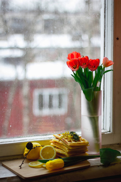 Vienna waffles and a bouquet of flowers on the window - Photo, Image