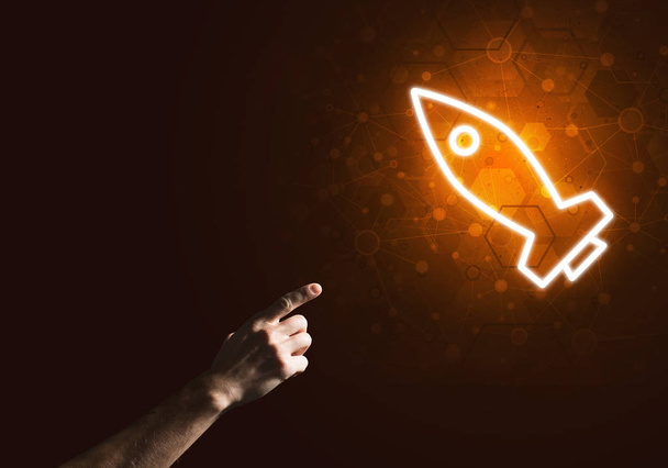 Rocket glowing icon and man hand on dark background - Fotoğraf, Görsel