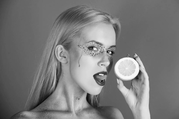 pretty blonde woman with creative fashionable makeup lick lemon, vitamin - 写真・画像