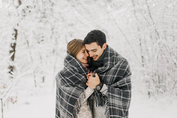Couple in love walking in the snowy forest, hugging, kissing and enjoying. - Photo, Image