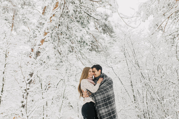Couple in love walking in the snowy forest, hugging, kissing and enjoying. - Foto, Imagem