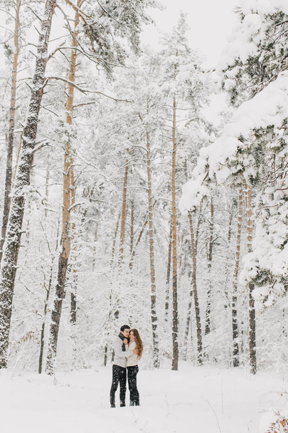 Couple in love walking in the snowy forest, hugging, kissing and enjoying. - Valokuva, kuva