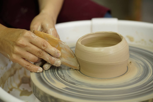 woman makes a jug with dirty arms on a Potter's wheel from raw wet clay - Photo, Image