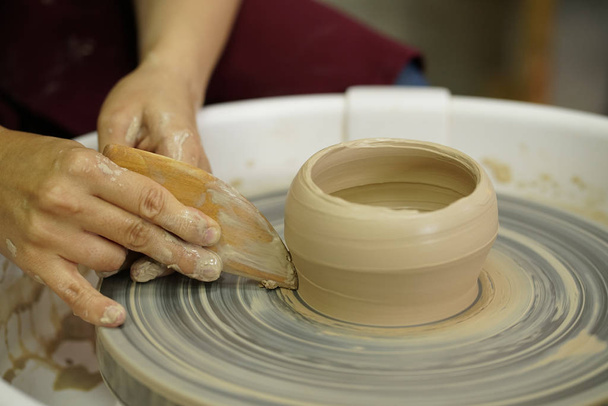 mujer hace una jarra con los brazos sucios en una rueda de Potter de arcilla húmeda cruda
 - Foto, Imagen