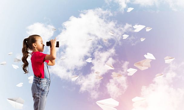 kleines süßes Mädchen in Overalls vor himmelblauem Hintergrund träumt von der Zukunft - Foto, Bild