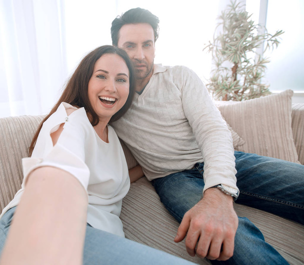 happy couple sitting on the couch in the living room - Foto, imagen
