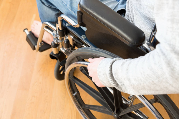 Detail of disabled man hand holding wheel of a wheelchair. - Foto, Imagen
