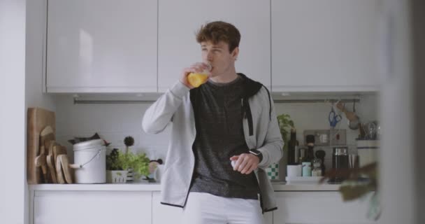 Young adult male drinking orange juice before after a run - Video
