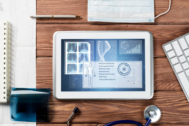 White tablet pc and doctor tools on wooden table - Foto, Bild