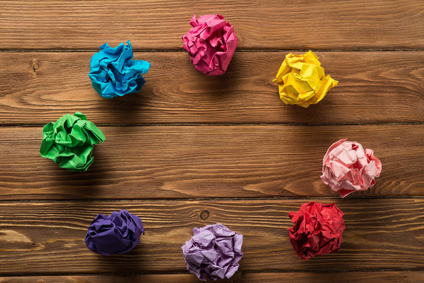 Set of multiple colorful crampled paper ball placed on wooden table as means of searching of new ideas. - Foto, imagen