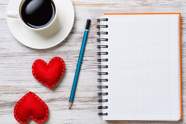 Coffee cup notepad pencil and two red hearts on wooden surface - Foto, Imagem
