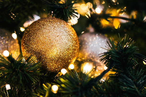 Пихтовая ветвь с шарами и праздничными огнями на рождественском фоне с блестками
. - Фото, изображение