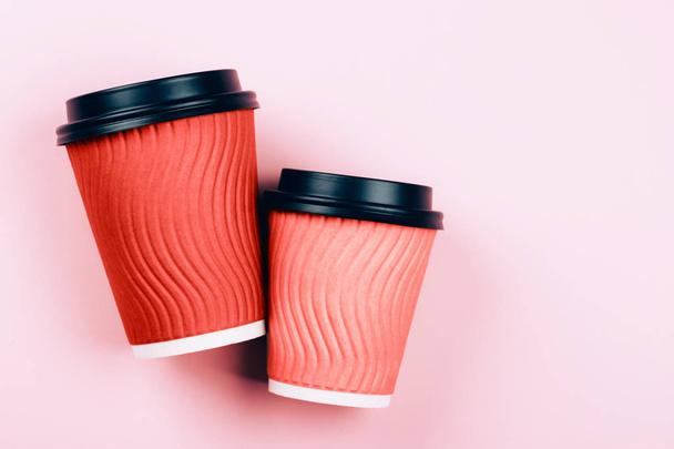 Two Living Coral cups of coffee to go on pastel pink background. Flat lay style. Place for text. - Фото, изображение
