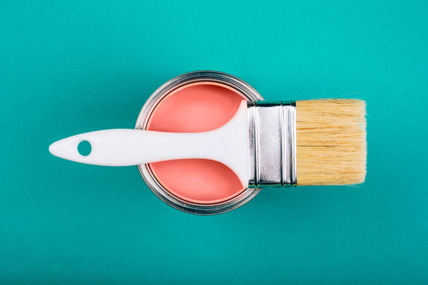 Brush with white handle on open can of Living Coral paint on blue pastel background. Color of the year 2019. Main trend concept. - Photo, Image