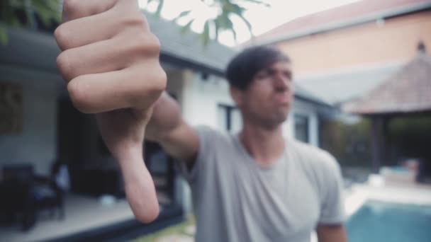 若い男、自宅で親指を屋外の中庭で。意見の相違の概念 - 映像、動画