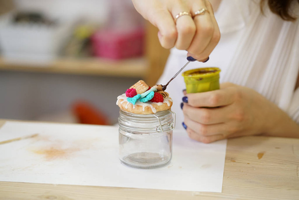 žena sedí u stolu bílá a vytváří sklenici kuchyň polymer clay dekorace v podobě listí a soubory cookie, krok za krokem mistrovskou třídu - Fotografie, Obrázek