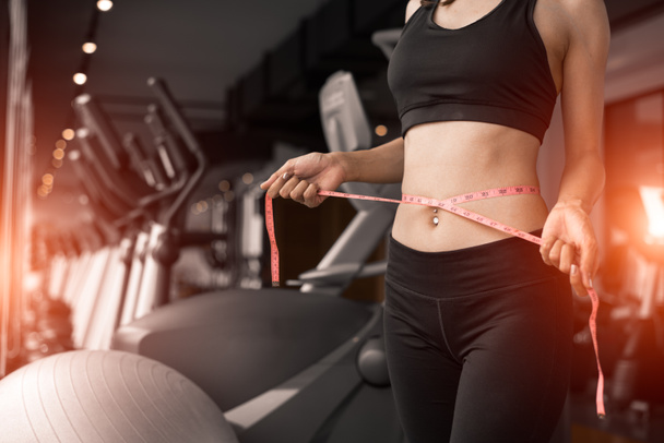 Sporty woman using waist tape line in fitness gym sport club training center near window with condominium background. Lifestyle of people workout exercise sport activity. Diet and weight loss theme. - Photo, Image