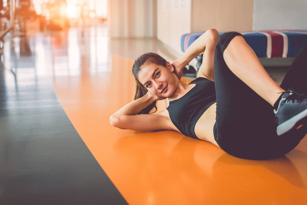 Sport woman doing sit up in fitness sport training club with sport equipment and accessories background. Workout crunch and bodybuilder. Lifestyles leisure and indoors activity. Cardio program concept - Foto, Imagen