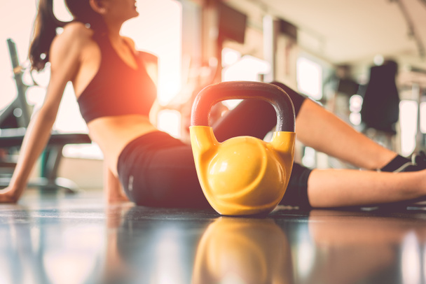 Εσωτερικη kettlebells με γυναίκα άσκηση προπόνηση στο γυμναστήριο fitness σπάσιμο Χαλαρώστε μετά από φόντο κέντρο κατάρτισης αθλητισμού. Υγιεινός τρόπος ζωής bodybuilding και αθλητής μυών αλτήρες. Υγειονομικής περίθαλψης στον τρόπο ζωής - Φωτογραφία, εικόνα