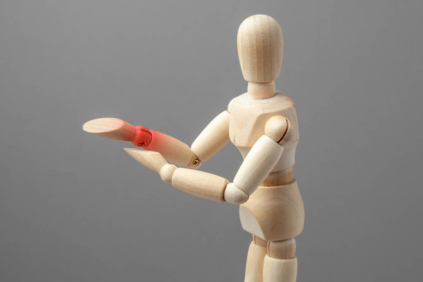 Joint pain forearm. The wooden man is holding his hand over his forearm in red - Foto, afbeelding