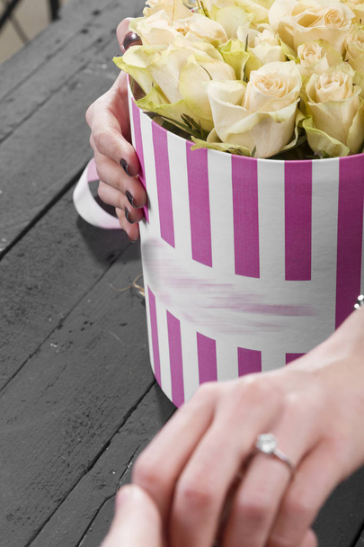 partial view of girlfriend holding boyfriend's hand and box with roses - Photo, Image