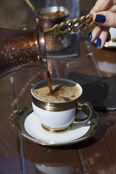 vista parcial de la mujer vertiendo café en la taza
 - Foto, Imagen