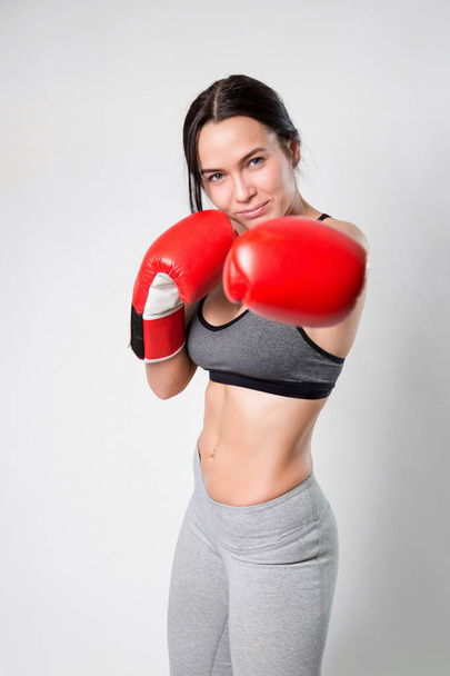 sportliches sexy Mädchen in Boxhandschuhen auf weißem Hintergrund. Volltreffer. - Foto, Bild