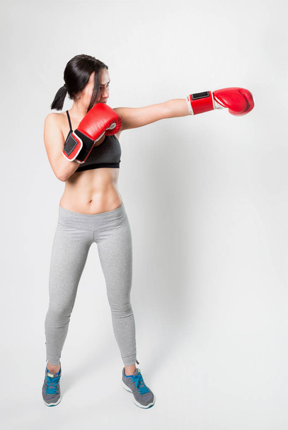 Sportieve sexy meisje in bokshandschoenen op een witte achtergrond. Voltreffer. - Foto, afbeelding