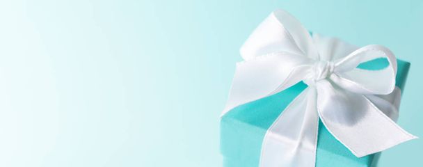 Close view of tiffany blue color box tied with silk ribbon on pastel blue background  - Φωτογραφία, εικόνα