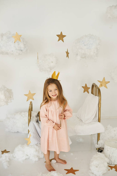 Little princess with a magic wand on  bed in a cloud on a white background - Foto, imagen